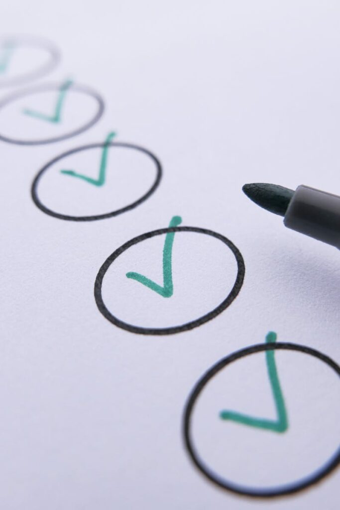 Close-up of a checklist with green checkmarks on white paper using a marker.